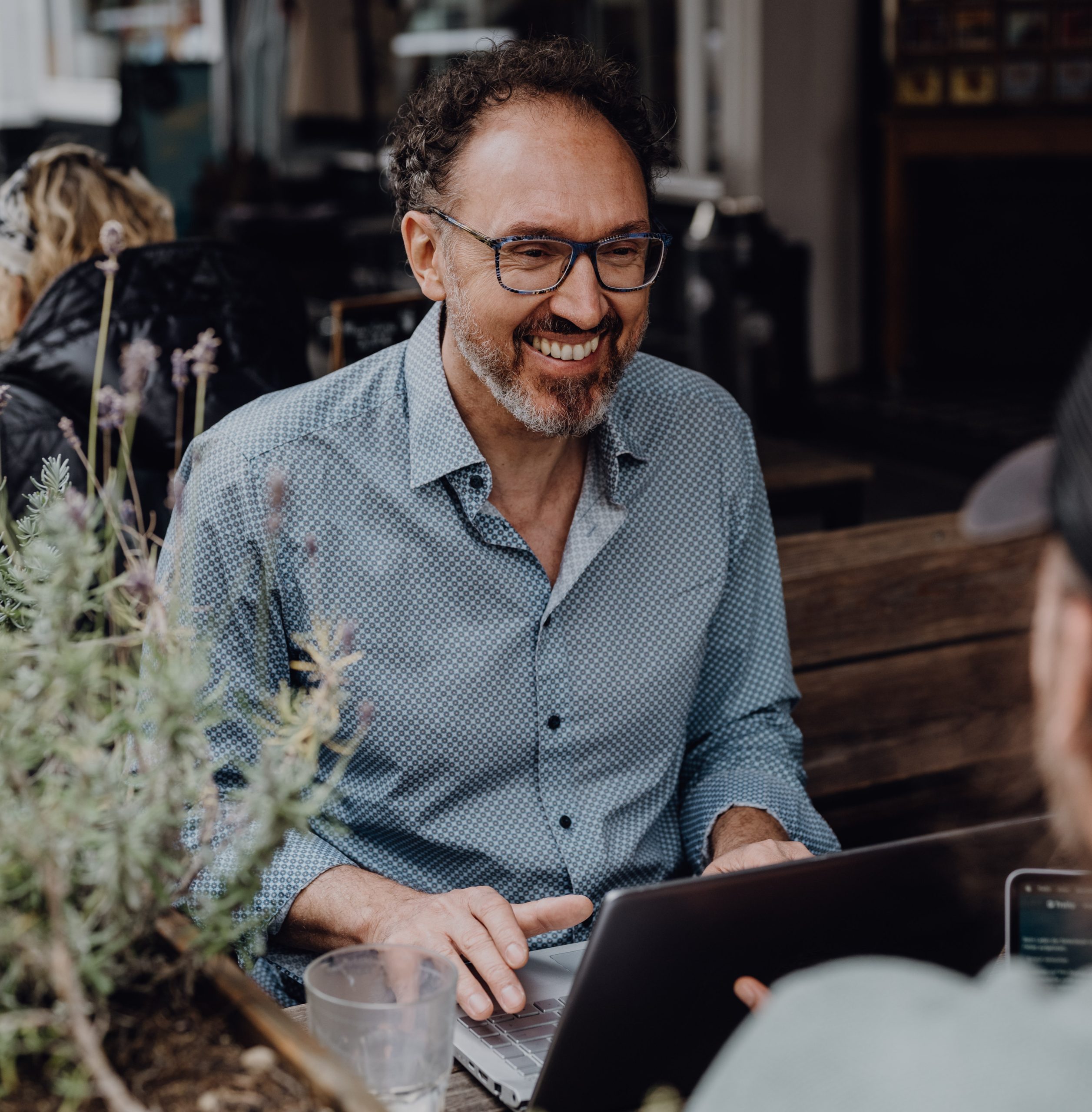 soyoma-yoga-michel-grumbach-businessyoga-sitzt-am Laptop-arbeitet-lächelt